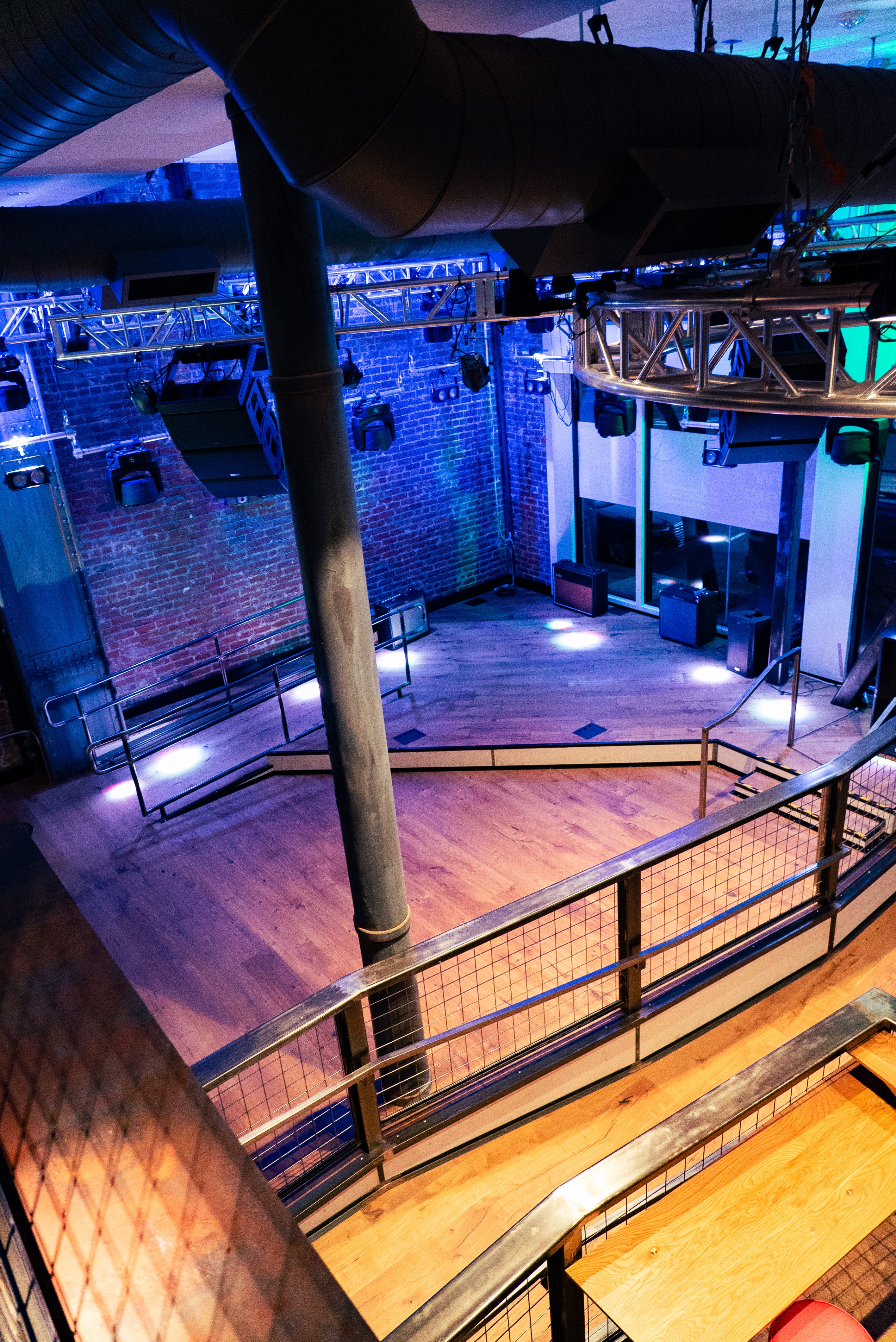 A dimly lit event space with a stage and metal railing.